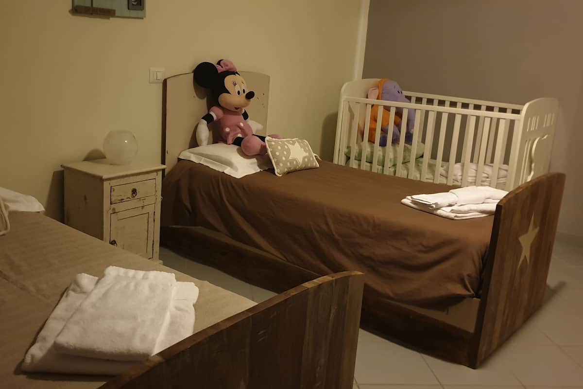 A child's bedroom with two beds, a crib, and stuffed toys.