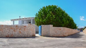 A modern building with a stone wall and a large tree in front.