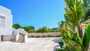 A modern building with a white exterior, a curved staircase, and a stone-paved courtyard.