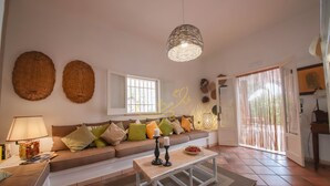Una sala de estar con un sofá, una mesa de centro, una lámpara y un colgador de mimbre.