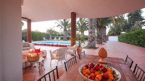 Un comedor con una mesa de madera, sillas de mimbre y un cuenco de fruta.