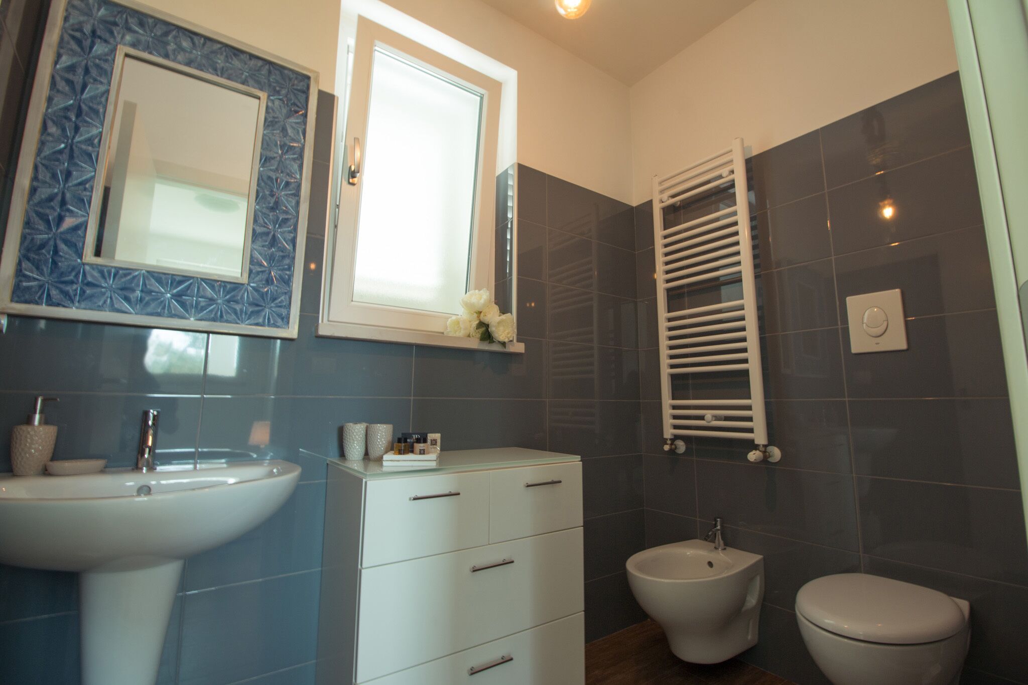 A bathroom with a sink, vanity, bidet, and a towel rack.