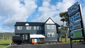 A lodge with a dark exterior, a white awning, and a signboard advertising various amenities including a hot air balloon experience. - Niseko OAC Lodge (Niseko)