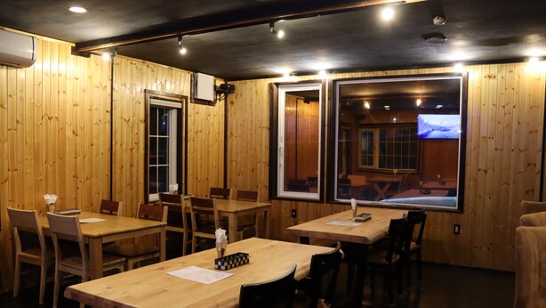 A restaurant with wooden walls and tables, featuring a large window with a view of a snowy landscape. - Niseko OAC Lodge (Niseko)