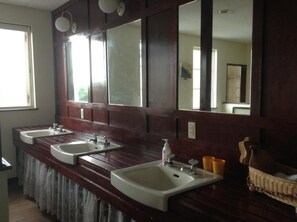 A bathroom with two sinks, a mirror, and a wicker basket. - Niseko OAC Lodge (Niseko)