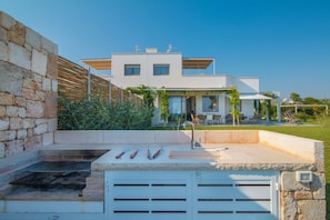 Una casa moderna con un muro in pietra, un'area barbecue e un patio con mobili da esterno.
