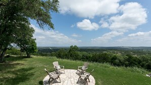 Une terrasse en pierre avec quatre chaises Adirondack et une vue sur une vallée.