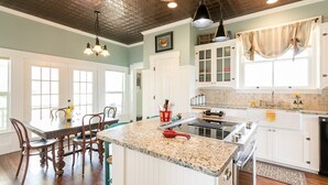 Una cocina amplia con una isla grande, armarios blancos y un comedor con sillas de madera.