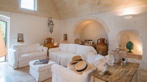 Un salón amplio con mobiliario blanco, techo de piedra y vistas al exterior.