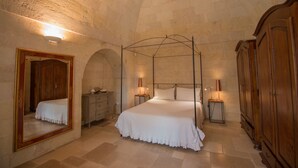 Un dormitorio con cama con dosel, un espejo grande, armario de madera y paredes de piedra.