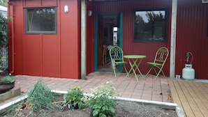 A red building with a patio area featuring two green chairs and a small table.