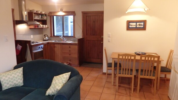 A compact living space with a kitchenette, a dining area, and a sofa with cushions.
