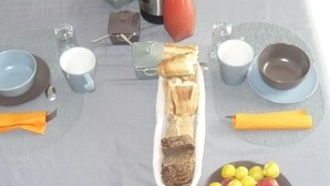 Een ontbijttafel gedekt met diverse soorten eten en drinken, waaronder fruit, gebak en een koffiepot.