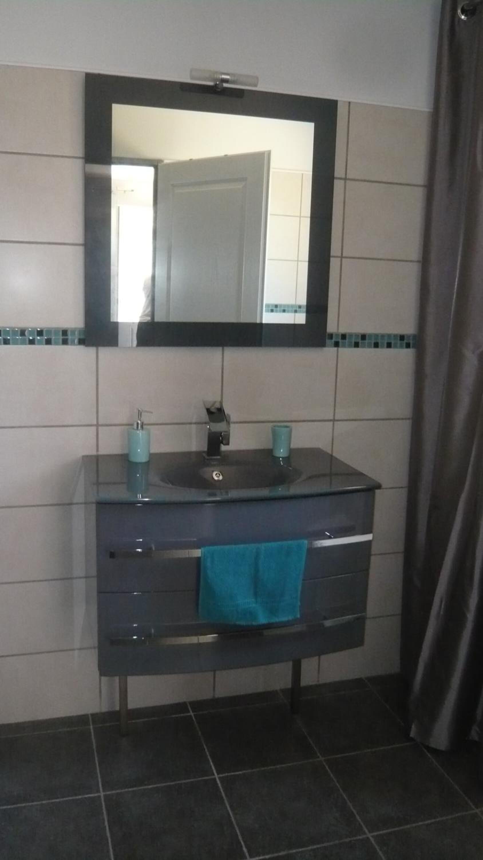 Un baño con un tocador oscuro, un espejo y un lavabo.