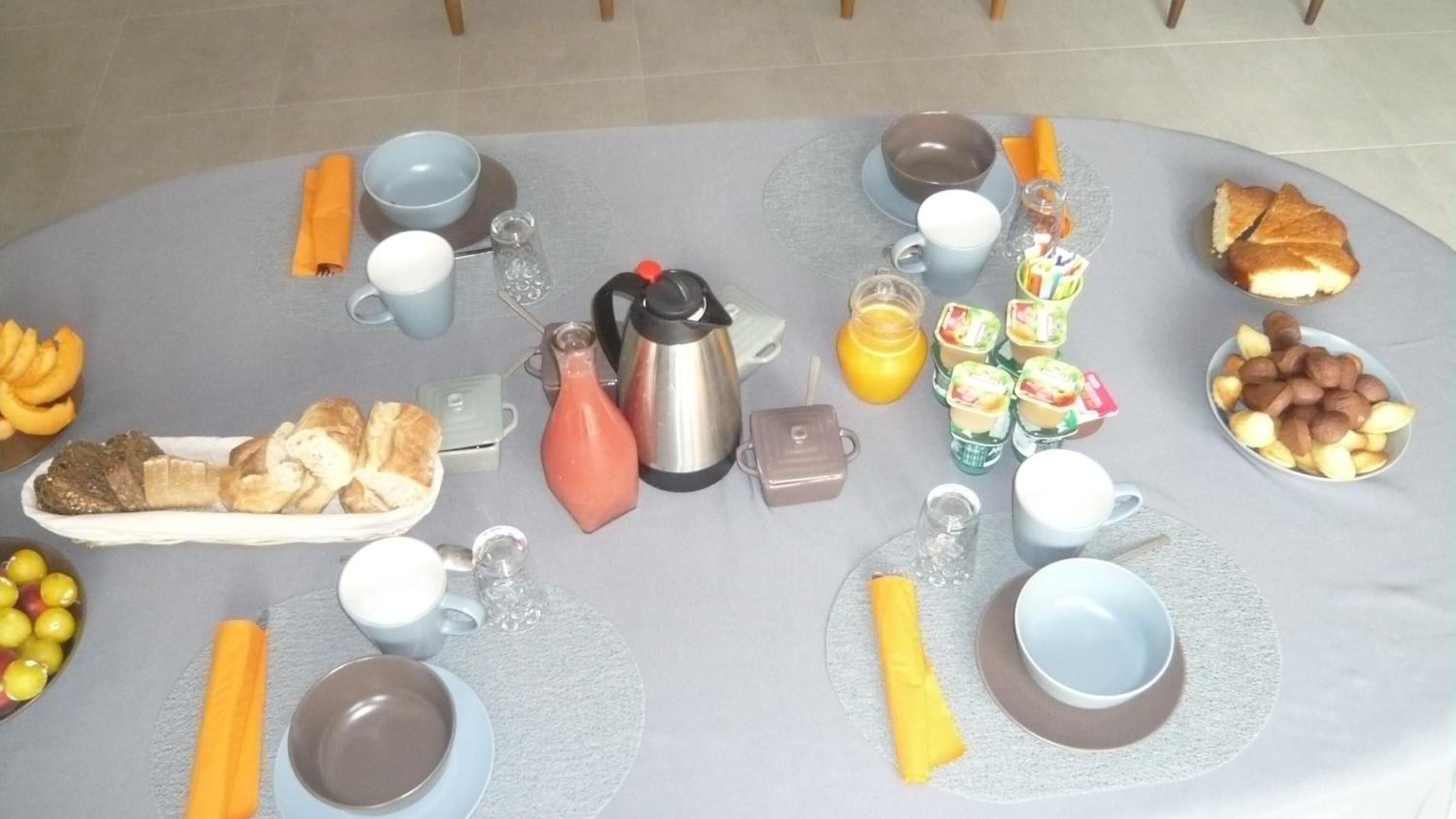 Ein Frühstückstisch mit verschiedenen Speisen, Tassen und einer Kaffeekanne.
