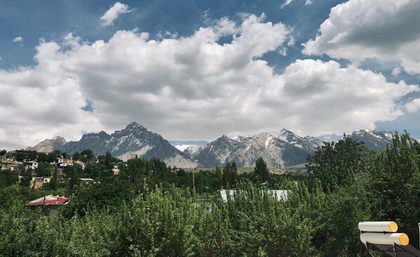 A mountainous landscape with a village in the foreground and snow-capped peaks in the background.