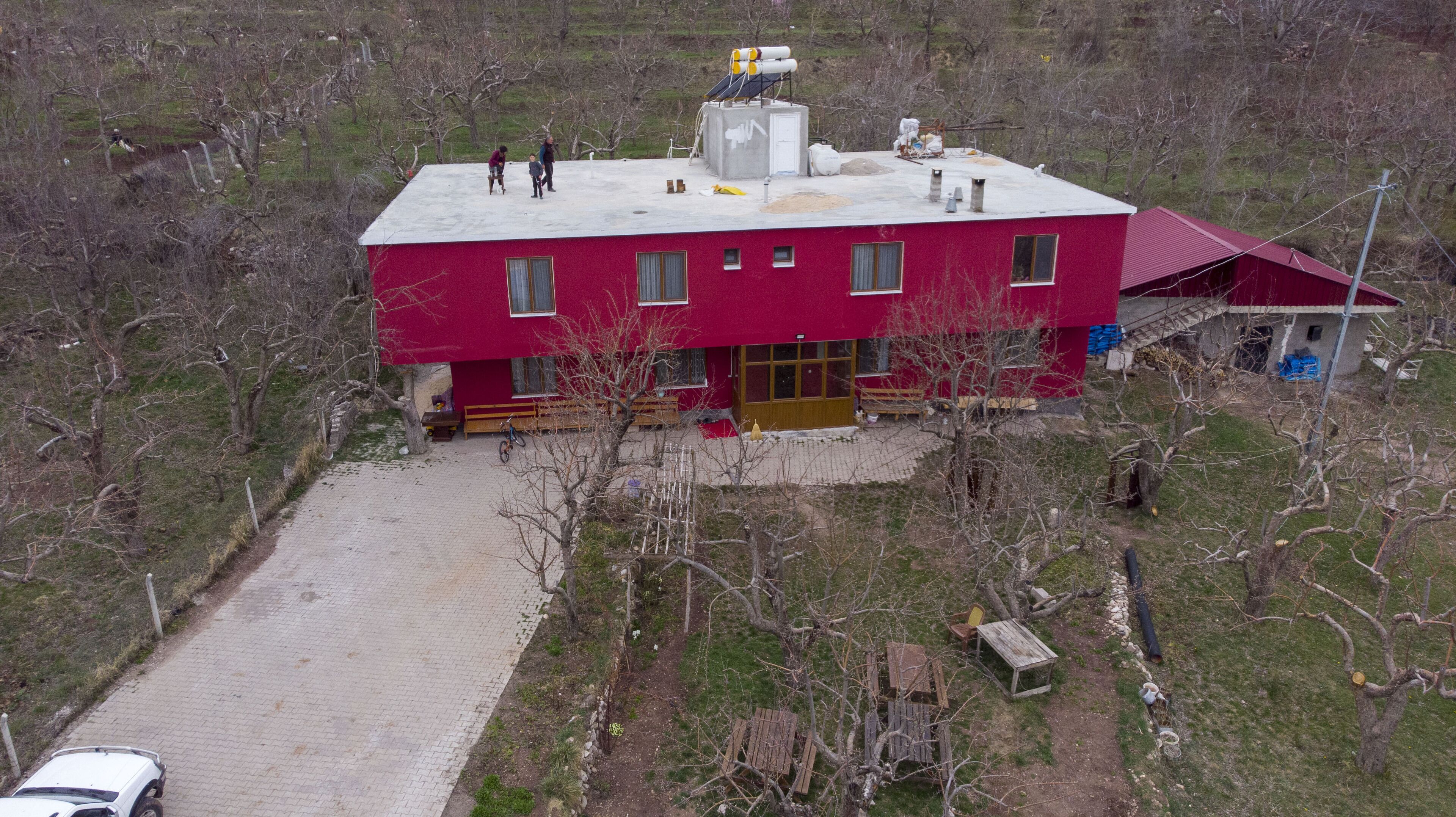 Una casa rossa a due piani con tetto rosso, vialetto lastricato e un piccolo portico.