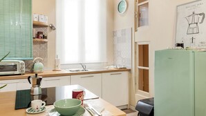 Une cuisine avec un plan de travail en bois, une machine à café, un saladier, une tasse et un réfrigérateur.