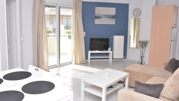 Ein modernes Wohnzimmer mit Fernseher, Sofa und Esstisch mit schwarzen, runden Untersetzern.