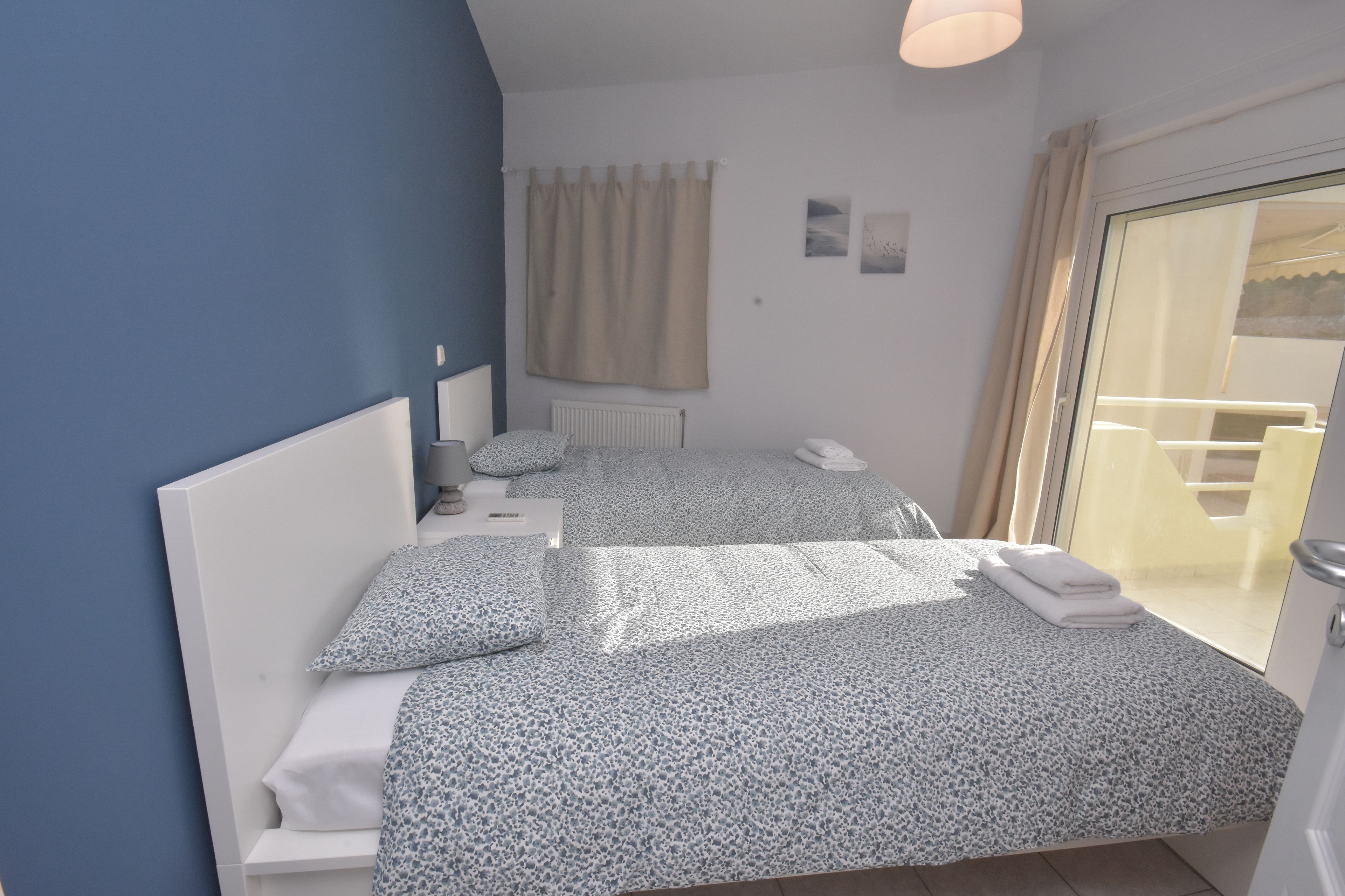 Una camera da letto con un letto, comodini, una finestra con tende e vista del balcone esterno.