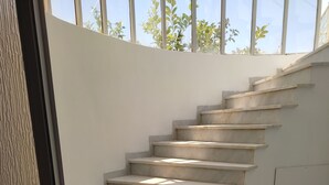 Eine Treppe aus Marmor führt zu einem Zwischenpodest mit einem dunklen Teppich am Fuß.