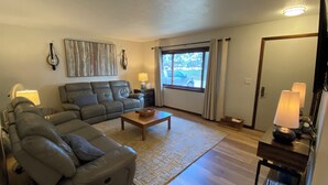 Een woonkamer met een hoekbank, een salontafel, een vloerkleed en een televisie op een meubel.