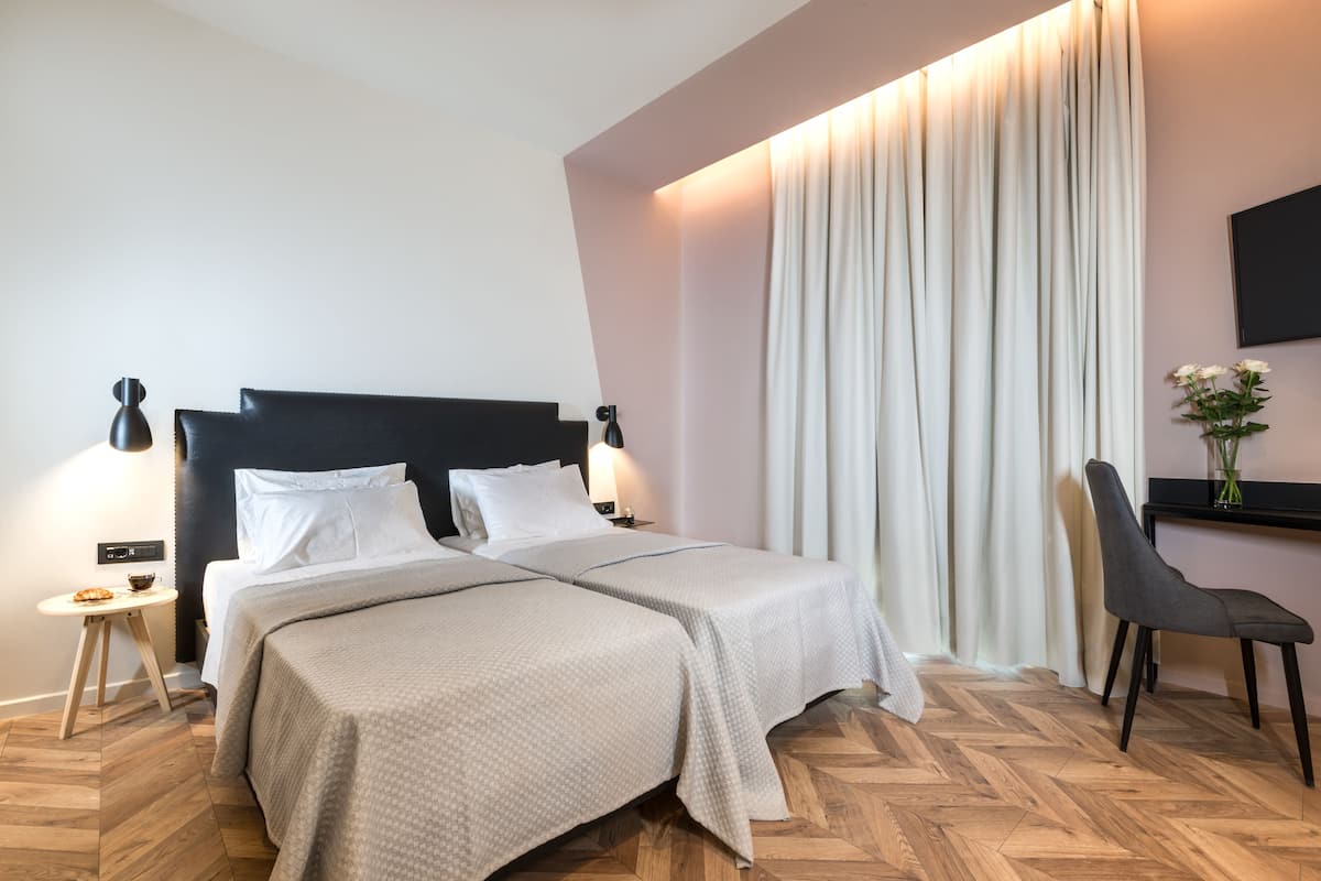 A double bed with a headboard, bedside tables, a chair, and a curtain.