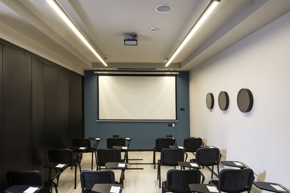 A conference room with a large screen, multiple chairs, and a projector.