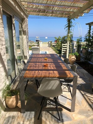 Une terrasse avec une table et des chaises en bois, donnant sur une zone côtière et offrant une vue dégagée sur la mer.