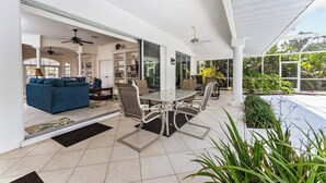 A covered patio with a dining table and chairs, a blue sofa, and a ceiling fan. - WATERFRONT, HEATED POOL, 3/2/2  single-family Rotonda West Home (Rotonda West)