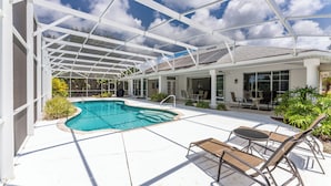 A covered outdoor swimming pool with lounge chairs and a patio area. - WATERFRONT, HEATED POOL, 3/2/2  single-family Rotonda West Home (Rotonda West)