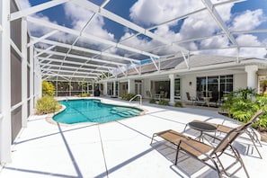 A covered outdoor swimming pool with lounge chairs and a patio area.