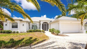 A two-story house with a garage, a driveway, and a well-maintained lawn. - WATERFRONT, HEATED POOL, 3/2/2  single-family Rotonda West Home (Rotonda West)