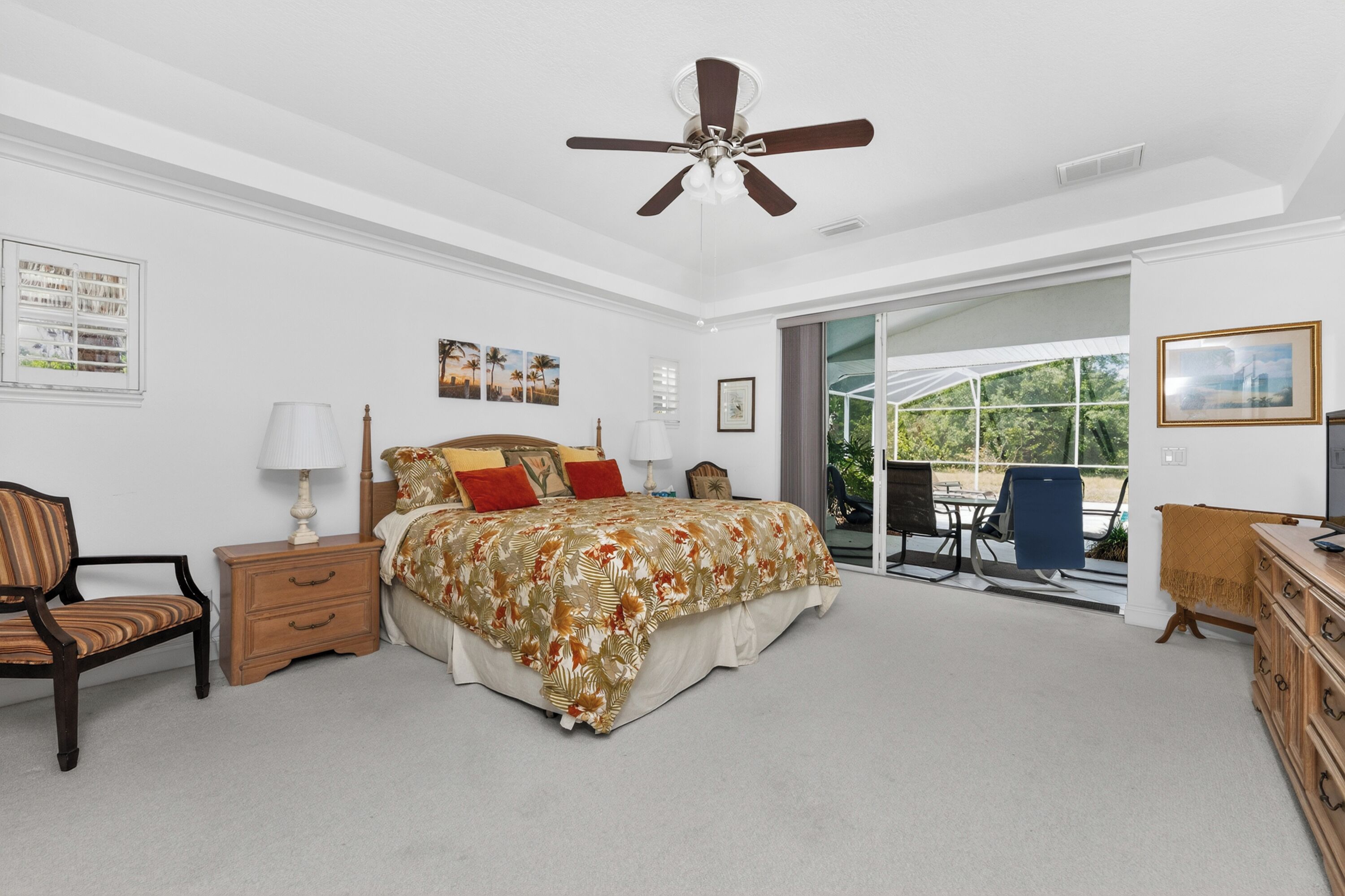 A bedroom with a bed, nightstand, chair, dresser, and a ceiling fan.
