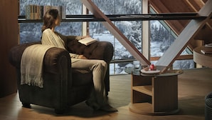 A cozy reading nook with a large window, wooden beams, and a leather armchair. - Lefay Resort & SPA Dolomiti (Pinzolo)