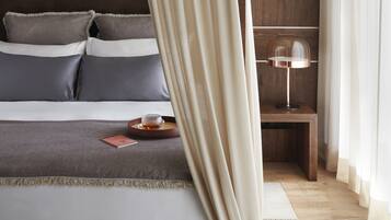 Un dormitorio con cama, mesita de noche, lámpara y cortinas.