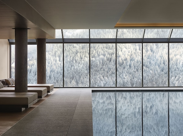 A modern interior with large windows, a seating area, and a view of a snowy forest. - Lefay Resort & SPA Dolomiti (Pinzolo)
