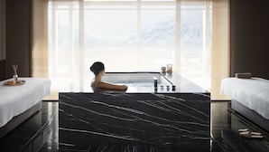 A spa room with a large bathtub, two beds, and a view of mountains through large windows. - Lefay Resort & SPA Dolomiti (Pinzolo)