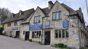 A stone building with multiple signs indicating it is a restaurant, bar, and inn.