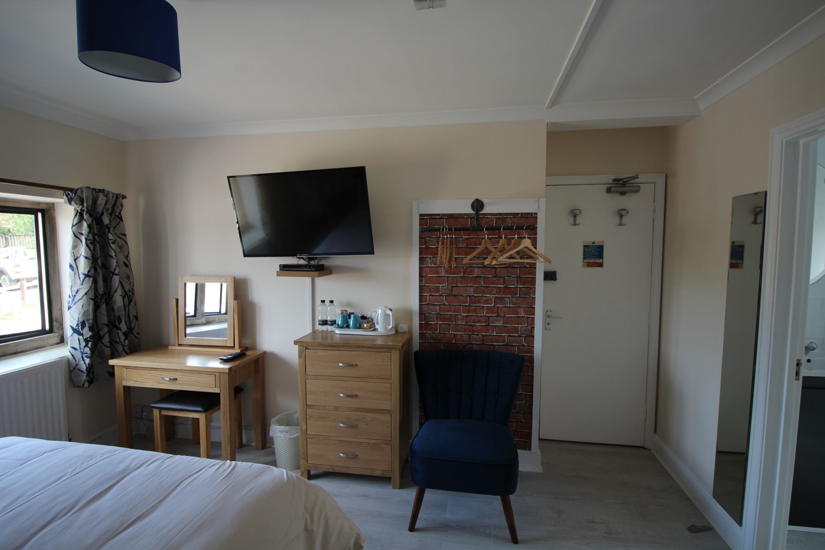 A hotel room with a bed, a desk with a chair, a television, and a wardrobe.