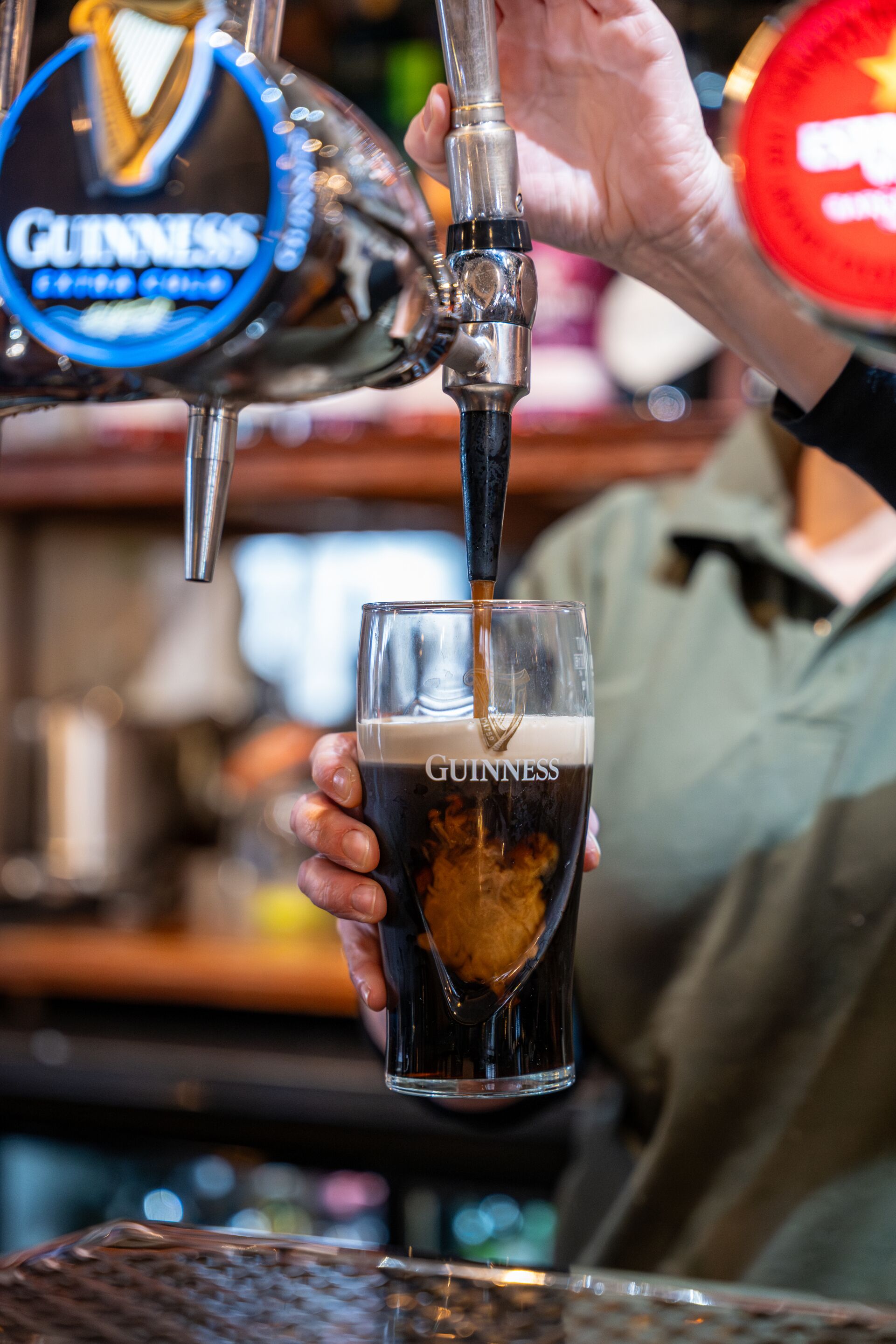 Une main verse de la bière Guinness dans un verre, et le nom de la marque est visible.