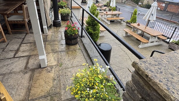 A stone terrace with outdoor seating, a view of the town, and a sign for 'The Cliffs Inn'.