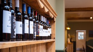 A wooden wine rack with bottles and glasses.
