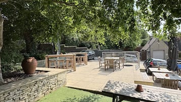 Un patio al aire libre con muros de piedra, césped y muebles de madera.