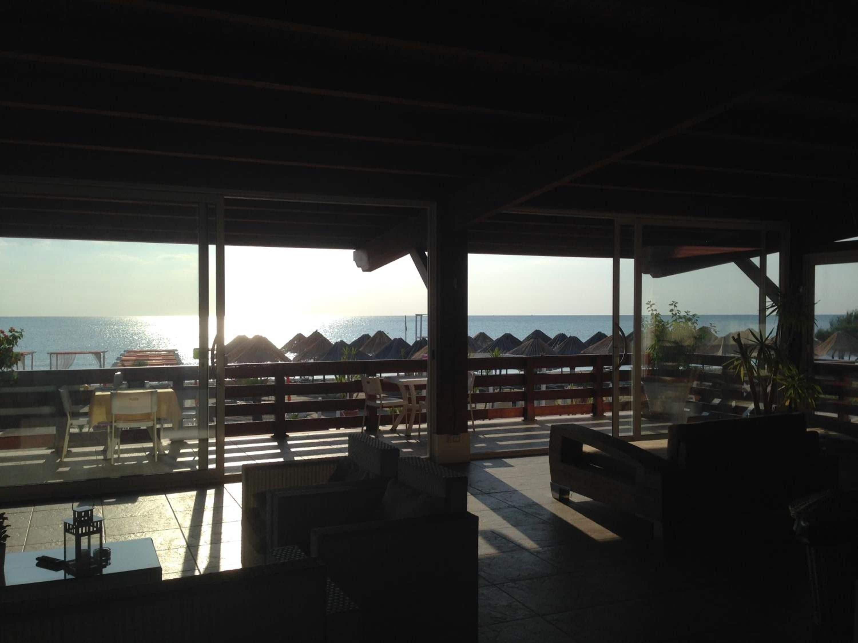 Un área de estar al aire libre con vista al mar, que incluye mesas y sillas.