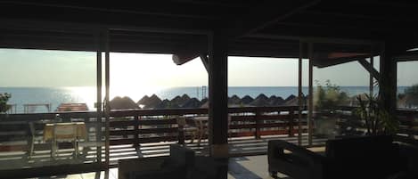 Un área de estar al aire libre con vista al mar, que incluye mesas y sillas.