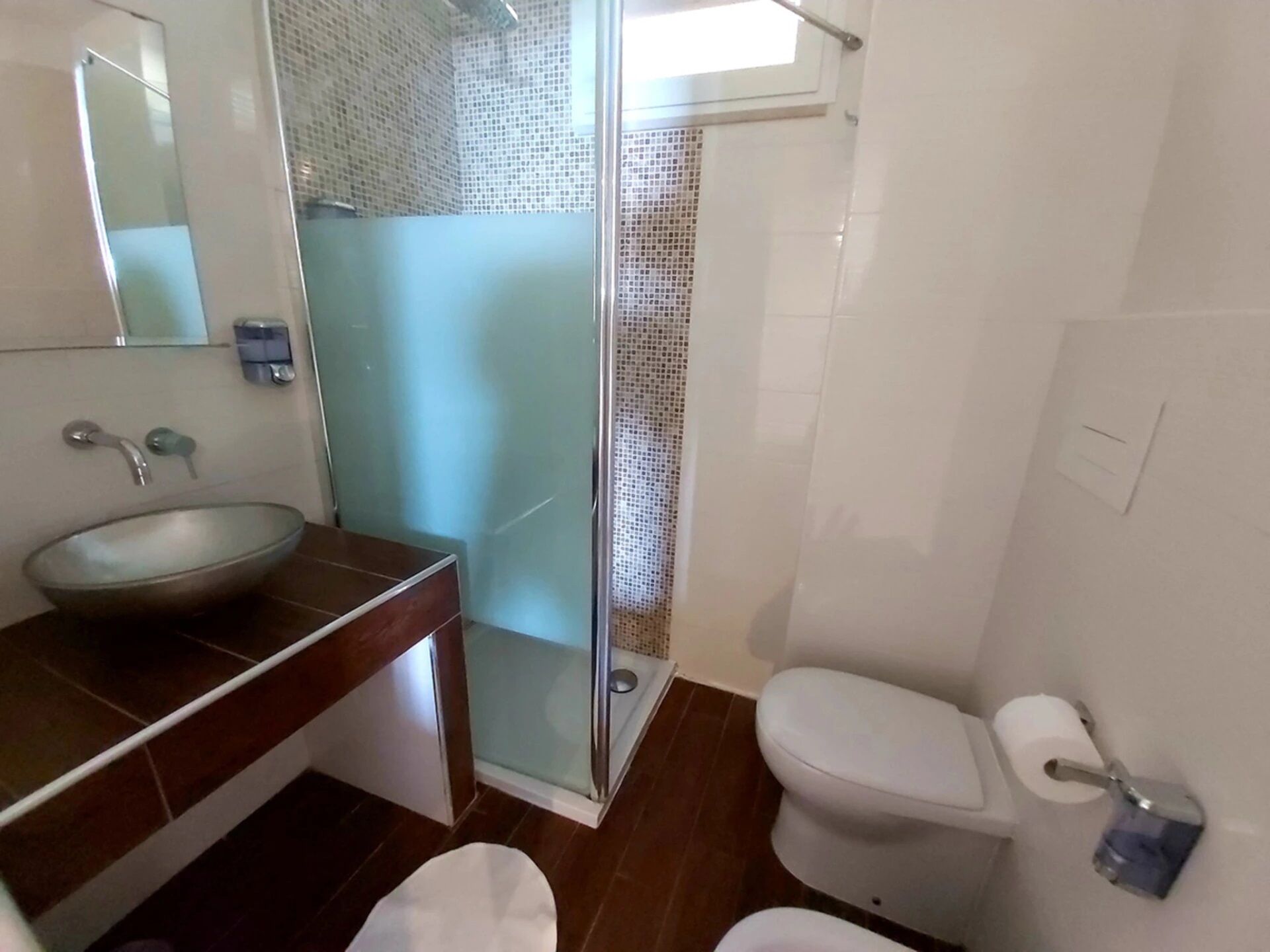 A bathroom with a glass shower enclosure, a sink, a toilet, and a mirror.