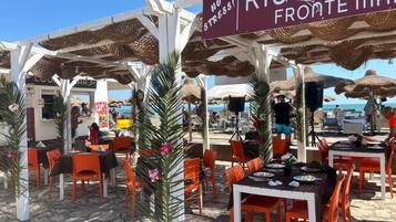 Een restaurant aan het strand met terras, een bord waarop 'RISTORAH FROMATE MARE' staat, en uitzicht op zee.