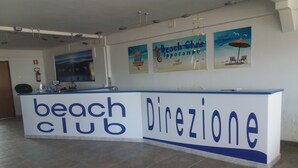 A reception desk labeled 'beach club' with a 'direzione' sign, indicating a direction or reception area. - Beach Club Ippocampo (Manfredonia)