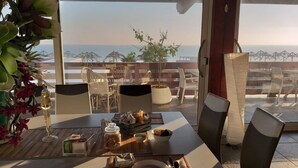 A dining area with a table set for two, a potted plant, and a view of the sea. - Beach Club Ippocampo (Manfredonia)